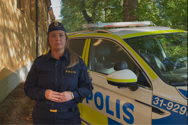 kvinlig polis i uniform står placerad framför en radiobil.